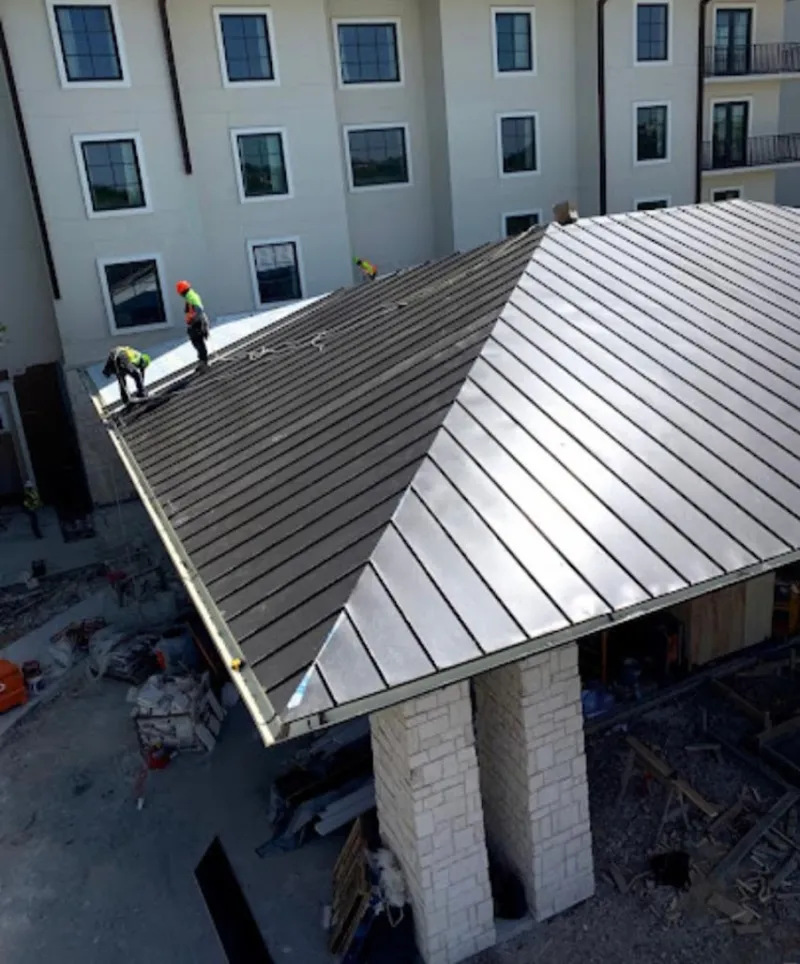 Crew installing standing seam metal roof panels on a commercial project in Crandall